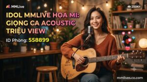 Banner hồ sơ Idol cover nhạc MMLive Họa Mi, ID phòng 558899. Hình ảnh nữ streamer xinh đẹp đang ôm đàn guitar acoustic mỉm cười trước micro trong không gian ấm cúng, kèm dòng chữ 'Giọng ca acoustic triệu view' và tên miền nanogate.io.